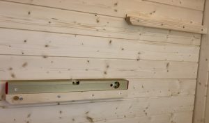 Auflageholz mit Wasserwaage ausrichten – Montage Saunabank Bildunterschrift: Das Auflageholz muss waagerecht montiert sein – Wasserwaage verwenden